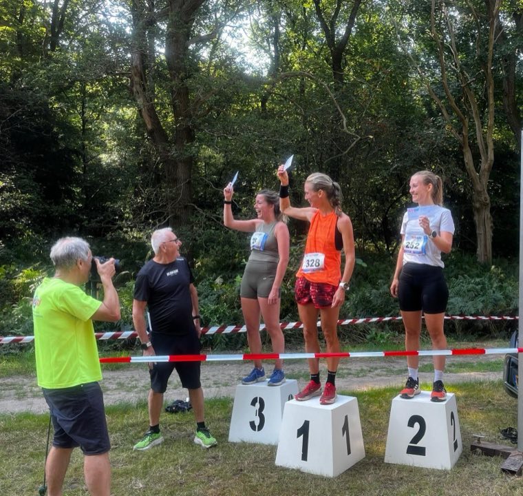 Drie hardloopsters op een podium in het bos. Ik sta rechts op plek twee, met startnummer 252.