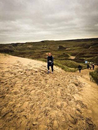 Een duin op rennen over los zand, met de duinen daarachter.